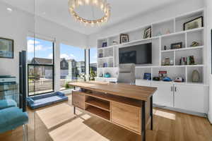 Home office with light wood-style flooring and a chandelier