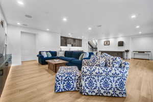 Living room with stairway, recessed lighting, and light wood-style floors
