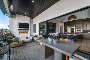 Wooden deck featuring outdoor dining space, an outdoor living space with a fireplace, and a sink