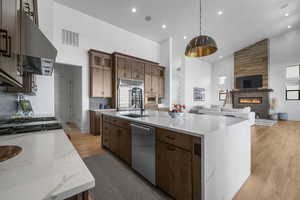 Kitchen with high vaulted ceiling, appliances with stainless steel finishes, range hood, open floor plan, and a sink