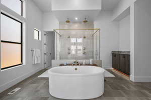 Bathroom with a shower stall, a freestanding tub, baseboards, and vanity