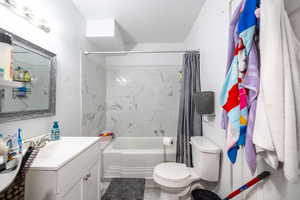 Bathroom with vanity, shower / bath combination with curtain, and toilet