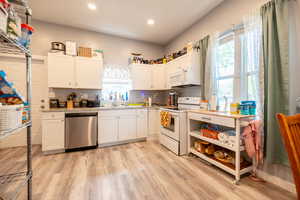 Kitchen featuring white appliances, plenty of natural light, light wood-type flooring, recessed lighting, and a sink