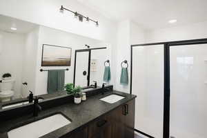 Full bathroom featuring toilet, a shower stall, double vanity, and recessed lighting