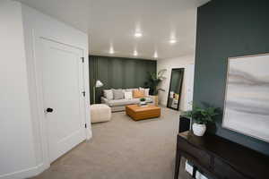 Living room with a decorative wall, carpet floors, and recessed lighting