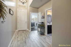 Foyer with light wood-style flooring, a chandelier, and baseboards