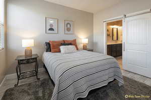 Bedroom with light wood-style floors, ensuite bath, and baseboards