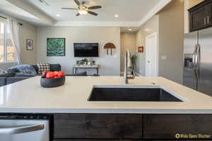 Kitchen with open floor plan, appliances with stainless steel finishes, a sink, dark brown cabinets, and a ceiling fan