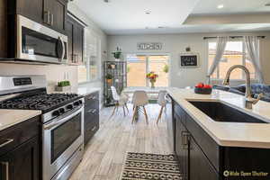 Kitchen featuring stainless steel appliances, a sink, light wood-style flooring, recessed lighting, and light stone countertops