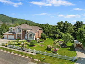 View of front of house with brick siding, concrete driveway, a mountain view, and a garage