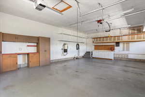 Garage featuring a garage door opener, a workshop area, and a central vacuum unit