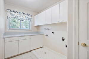 Washroom featuring cabinet space, hookup for an electric dryer, and light tile patterned floors