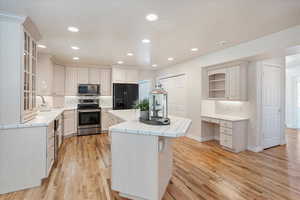 Kitchen featuring stainless steel appliances, tile countertops, a center island, decorative backsplash, and light wood-type flooring