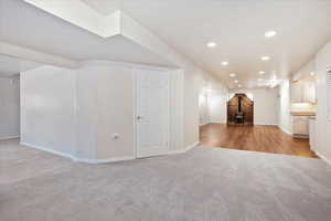 Unfurnished living room with light carpet, baseboards, a wood stove, and recessed lighting