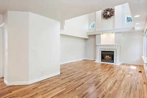 Unfurnished living room with wood finished floors, a tile fireplace, baseboards, and recessed lighting