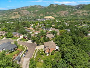Aerial view of property and surrounding area featuring mountains and nearby suburban area