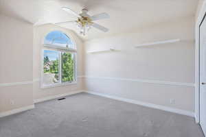 Empty room with vaulted ceiling, carpet flooring, baseboards, a ceiling fan, and a textured ceiling