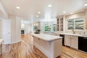 Kitchen featuring dishwasher, tile counters, a sink, light wood finished floors, and recessed lighting