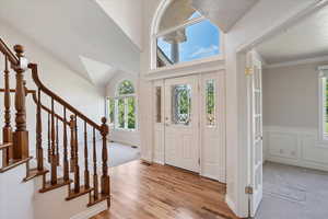 Foyer with stairs, light wood-type flooring, and light carpet