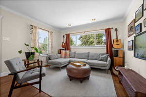 Living area featuring wood finished floors, ornamental molding, baseboards, and recessed lighting