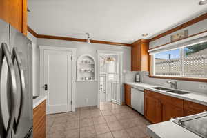 Kitchen featuring stainless steel appliances, a sink, light countertops, brown cabinetry, and tasteful backsplash