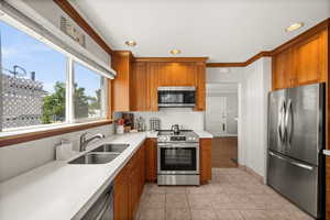 Kitchen featuring stainless steel appliances, a sink, decorative backsplash, brown cabinets, and recessed lighting