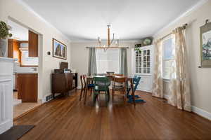 Dining space featuring a chandelier, wood finished floors, crown molding, and baseboards