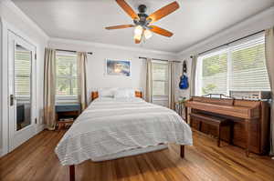Bedroom featuring wood finished floors, ornamental molding, and a ceiling fan