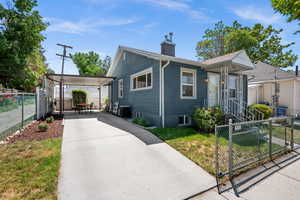 View of front of house with concrete driveway, a chimney, and a carport