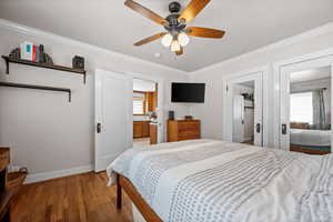 Bedroom featuring baseboards, light wood finished floors, ornamental molding, a ceiling fan, and ensuite bath