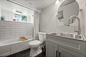 Full bathroom featuring toilet, shower / bathtub combination with curtain, and vanity