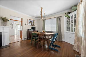 Dining area with a chandelier, wood finished floors, crown molding, and baseboards