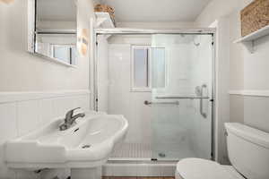 Full bath with toilet, a shower stall, and tile walls