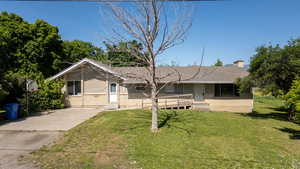 View of front of home with brick siding, a front yard, driveway, and a chimney