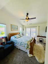 Carpeted bedroom with access to outside, multiple windows, vaulted ceiling, ceiling fan, and a textured ceiling