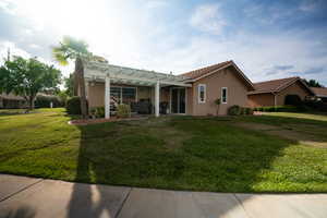 View of front of property featuring a pergola, stucco siding, a front yard, a tiled roof, and a patio
