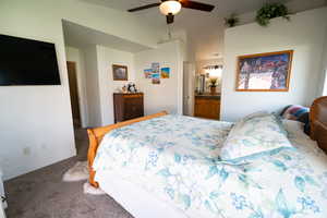 Bedroom with carpet flooring, lofted ceiling, baseboards, a ceiling fan, and ensuite bath