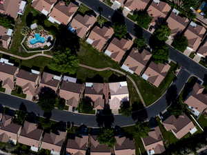 Aerial view of property and surrounding area featuring nearby suburban area and a pool