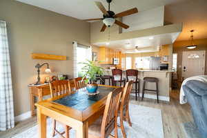 Dining space with a ceiling fan, light wood finished floors, and baseboards