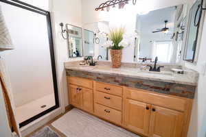 Full bath with a shower stall, double vanity, and ceiling fan