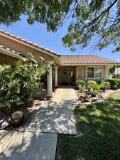 View of front of home featuring a tiled roof, a front yard, and stucco siding