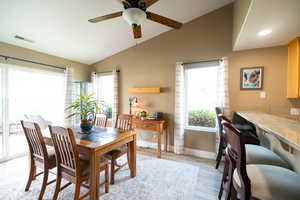 Dining space with lofted ceiling, healthy amount of natural light, a ceiling fan, light wood-style flooring, and baseboards