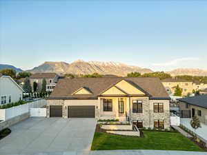 View of front of house featuring stone siding, a mountain view, a garage, and a gate