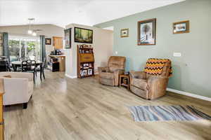 Living area with light wood-style floors, baseboards, and lofted ceiling