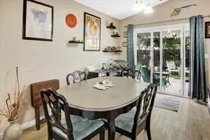Dining area with wood finished floors and vaulted ceiling