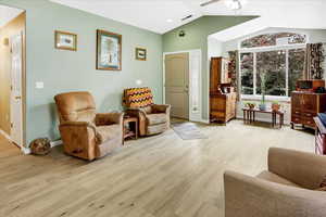 Living room with ceiling fan, light wood-style floors, lofted ceiling, and baseboards
