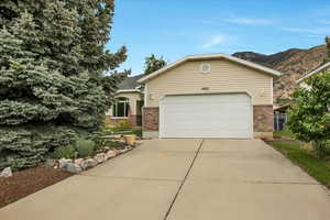 Single story home with brick siding, driveway, a garage, and a mountain view