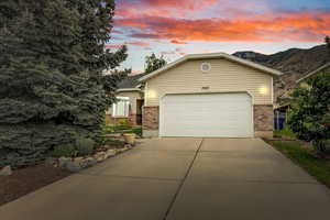 View of front of home with brick siding, driveway, an attached garage, and a mountain view