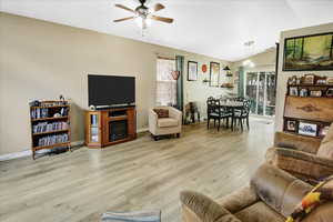 Living room with a ceiling fan, wood finished floors, vaulted ceiling, and baseboards
