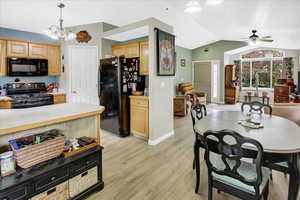 Kitchen featuring black appliances, vaulted ceiling, light countertops, light brown cabinetry, and ceiling fan